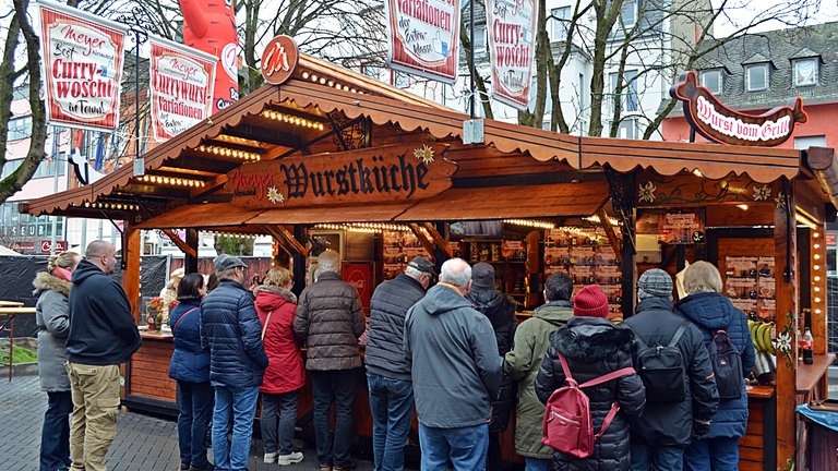 Besucherinnen und Besucher stehen beim Currywurstfestival 2025 vor einem Wurststand Schlange.