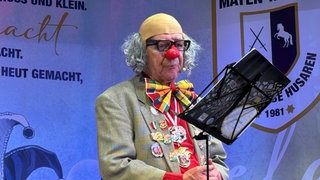 Stefan Zlotnik steht als Clown verkleidet auf der Bühne und hält eine Büttenrede.