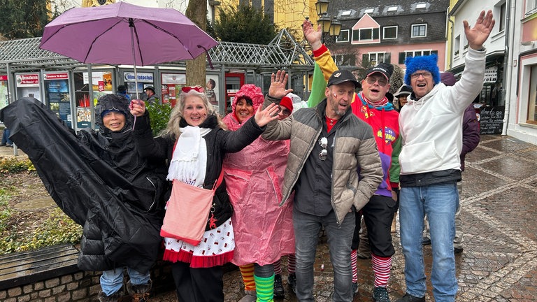 Eine Gruppe Zuschauer in Regenkleidung freut sich in Ahrweiler über den Rosenmontagsumzug 2026.