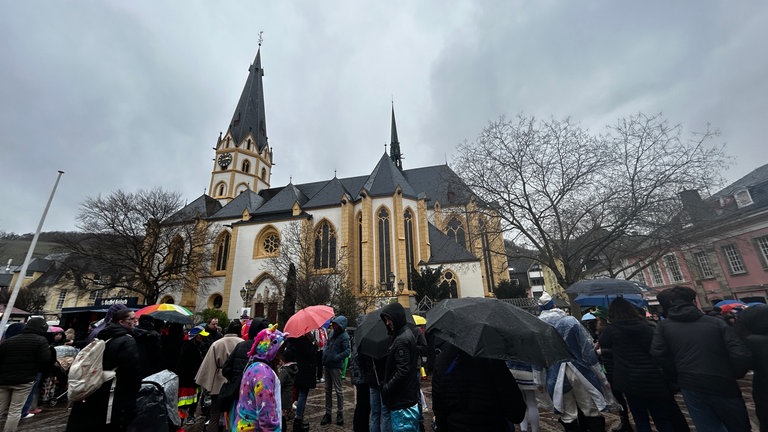 Die Kirche in Ahrweiler, davor dicht gedrängt Menschen mit Regenschirmen: Beim Rosenmontagsumzug in Ahrweiler war es grau und naß. 