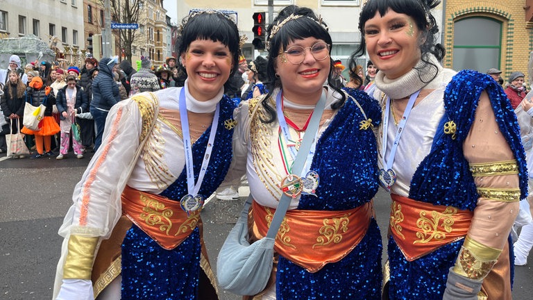 Drei kostümierte Frauen am Straßenrand beim Rosenmontagszug in Koblenz