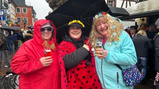 Drei kostümierte Frauen lachen beim Rosenmontagsumzug 2026 in Ahrweiler in die Kamera