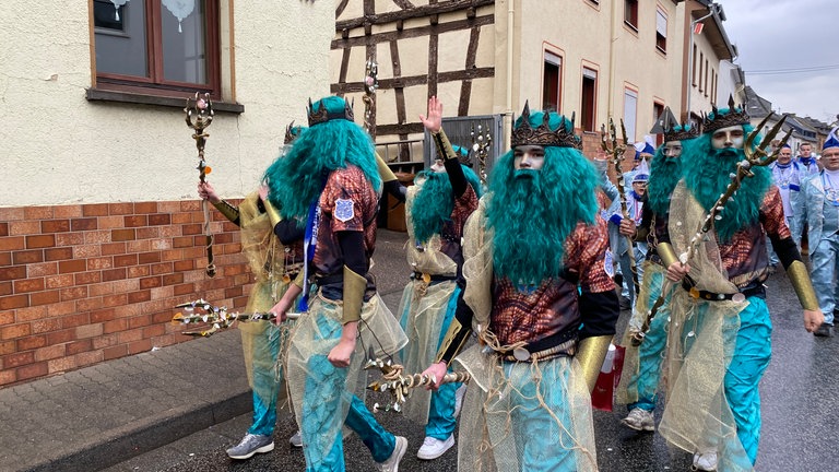 Ein Gruppe junger Männer, die als Wassermänner mit smaragdgrünen Perücken und Bärten verkleidet sind: Aufmarsch der Karnevalisten vor dem großen Veilchendienstagsumzug im Neuwieder Stadtteil Heimbach-Weis.