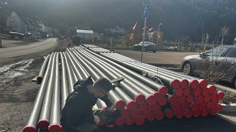 Projektleiter Nik Kozisek zeigt Rohre des kalten Nahwärmenetzes in Rech. Sie werden im Boden verlegt und transportieren Sole aus den Erdwärmesonden zu den angeschlossenen Häusern.