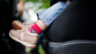 Ein Kleinkind in einem Kindersitz. Eine Mutter ist angeklagt, weil sie ihr Kind in Wissen bei Hitze alleine im Auto ließ.
