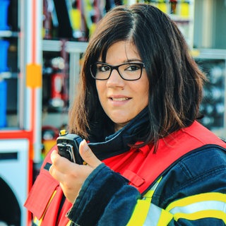 Feuerwehrfrau Nicole Werner mit Gruppenführer-Weste und Funkgerät in der Hand