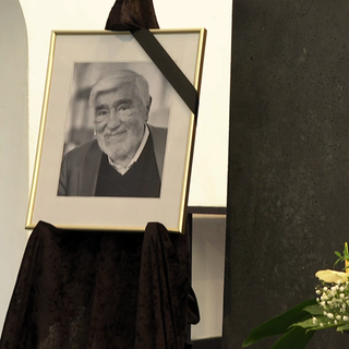 Ein Foto von Mario Adorf neben Blumengebinde - Mayen gedenkt des verstorbenen Schauspielers