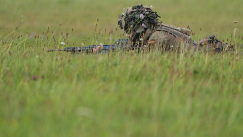Ein Soldat liegt mit einem Gewehr im tiefen Gras auf einer Wiese: Auch im Norden von RLP macht die Bundeswehr bei der Übung "Gelber Merkur" mit.