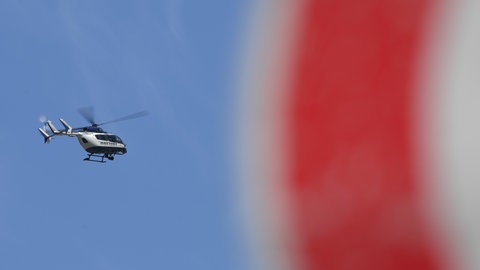 Ein Polizeihubschrauber fliegt vor blauem Himmel.