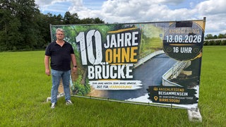 Uwe Igelmund Ortsvorsteher (CDU) von Birresdorf vor dem großen Transparent zur Kundgebung für eine neue Brücke. 