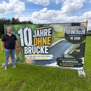 Uwe Igelmund Ortsvorsteher (CDU) von Birresdorf vor dem großen Transparent zur Kundgebung für eine neue Brücke. 