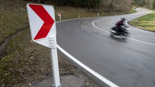 Ein Motorradfahrer fährt auf einer Landstraße und ist unscharf zu sehen, da er schnell fährt.