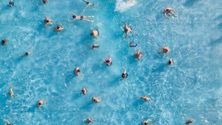 Zahlreiche Badegäste sind in einem Freibad im Wasserbecken (Aufnahme mit einer Drohne).