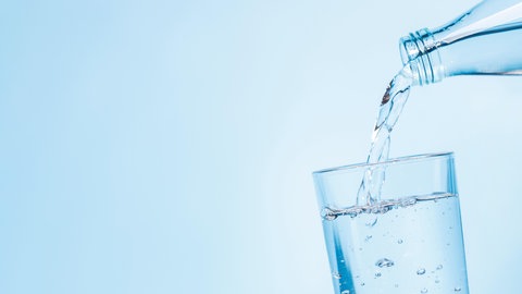 Wasser fließt in ein Glas- Wegen der großen Hitze rufen Kommunen zum Wassersparen auf