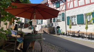 Die Figur einer Frau unter einem Sonnenschirm in einer Gasse in Bremm an der Mosel. Laut des Magazins Geo ist es eines der schönsten Dörfer in Deutschland. 