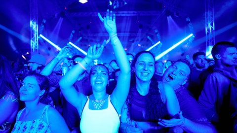 Besucherinnen und Besucher tanzen vor einer Festivalbühne.
