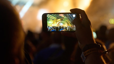 Mit dem Handy wird die Lichtershow des Festivals eingefangen.