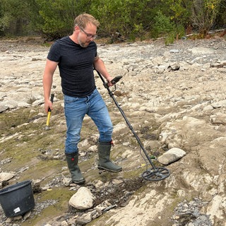 Schatzsucher Christian Ganser ist bei Niedrigwasser mit seinem Metalldetektor am Rheinufer unterwegs