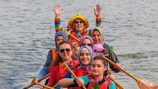 Ein Paddelboot mit vielen Menschen, die glücklich in die Kamera strahlen