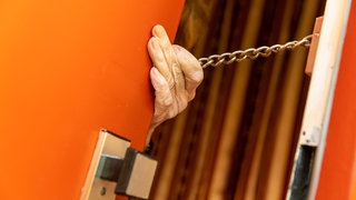 Seniorin an der Haustür mit Kette an der Tür: Symbolbild für Seniorin in Neustadt an ihrer Haustür um mehrere tausend Euro gebracht
