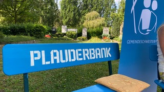 Gemeindeschwester-Plus Heidi Gangkofner sitzt auf ihrer Plauderbank auf dem Friedhof Speyer.