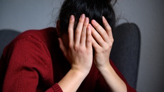 Eine Frau hält verzweifelt die Hände vors Gesicht