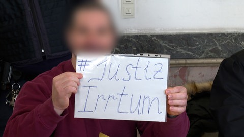 Nach der Urteilsverkündung hielt der Mann ein Schild hoch: "Justizirrtum"