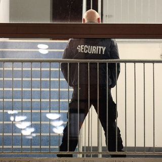 Ein Mitarbeiter eines Sicherheitsdiensts bewacht ein Gebäude (Symbolbild)