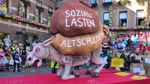 Motivwagen mit Esel und Fußgruppe mit Städtevertretern im Jutesack auf Düsseldorfer Rosenmontagsumzug 