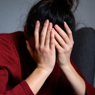 Eine Frau sitzt mit dem Kopf in den Händen auf einem Stuhl (gestellte Szene). Symbolbild. Psychiater von der pfälzischen Resilienz-Initiative spricht über mentale Gesundheit.