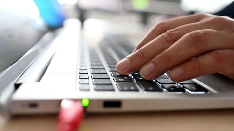 Hände auf einer Laptop-Tastatur: Künstliche Intelligenz nutzen Kriminelle jetzt für Betrugsmaschen