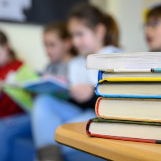 An der Gräfenauschule in Ludwigshafen bleiben vermutlich wieder mehr als 30 Kinder sitzen. (Symbolbild) Kinder sitzen im Klassenzimmer und lesen ein Buch.