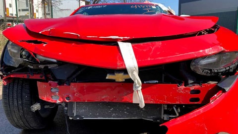 Demolierte Kühlerhaube eines roten Schrottautos: Ein Autohaus soll Betrug mit stark beschädigten Autos begangen haben.