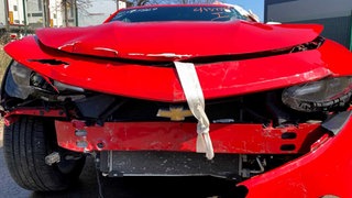Demolierte Kühlerhaube eines roten Schrottautos: Ein Autohaus soll Betrug mit stark beschädigten Autos begangen haben.