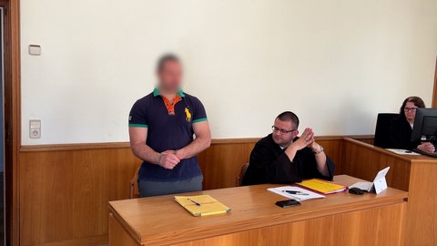Der mutmaßliche Fluchthelfer (links) steht neben seinem Verteidiger beim Prozess vor dem Landgericht in Landau.