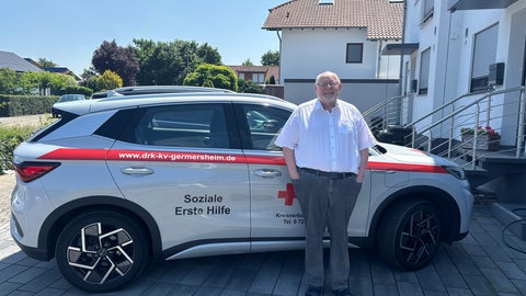 Heiner Butz vor einem Auto mit der Aufschrift "Soziale Erste Hilfe"