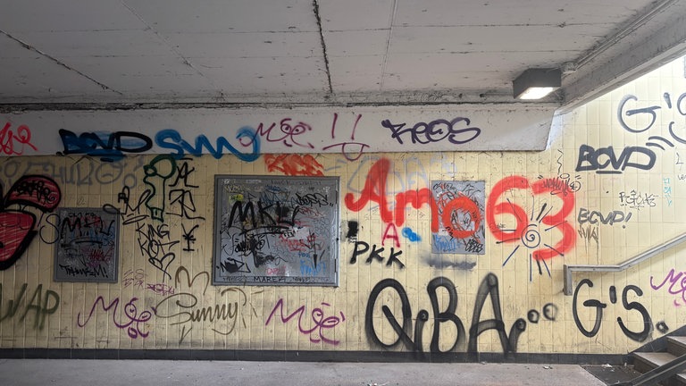 Rosa Grafffiti vor gelber Wand