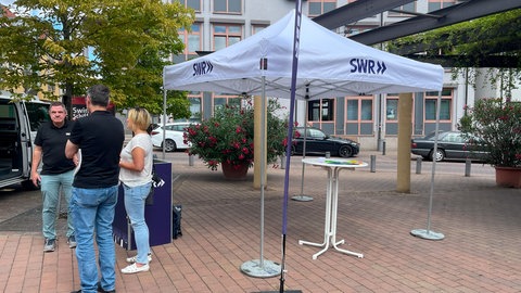 SWR Aktuell vor Ort in Schifferstadt: Reporter Frank Schumann und der Leiter des SWR Studios Ludwigshafen Hartmut Reitz  im Gespräch am SWR Stand auf dem Schillerplatz in Schifferstadt.