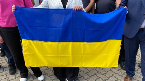 Ukrainische Flagge. Die ukrainische Delegation zeigt Flagge beim Abschlussfoto. Aus Sicherheitsgründen können die Gesichter der ukrainischen Feuerwehrmänner nicht gezeigt werden.