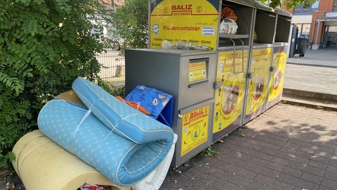 Sperrmüll lagert neben einem Altkleider-Container einer bayerischen Textilrecycling Firma, die noch mehrere Container in der Pfalz betreibt.