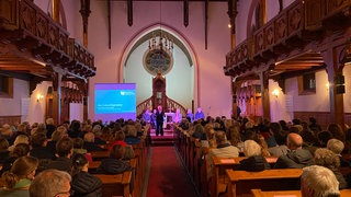 Eine Kirche mit versammelten Menschen - hier wird über den Sparkurs der evangelischen Kirche der Pfalz diskutiert.