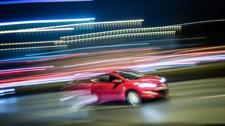 Ein Auto rast im Dunkeln über eine Straße - Symbolbild: 35-jähriger Raser zu Bewährungsstrafe verurteilt - er hatte unter anderem an illegalen Autorennen teilgenommen