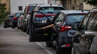 Ein Mann schließt die Tür eines Autos