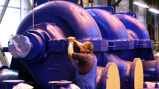 An überdimensionalen Wasserpumpen prüft ein Mitarbeiter bei KSB die Schraubverbindungen.