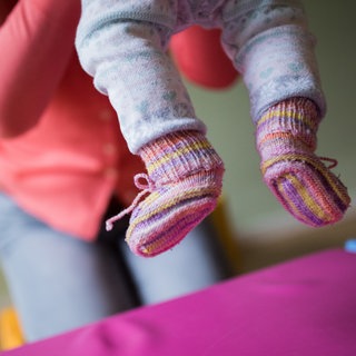 Eine Tagesmutter hebt ein kleines Kind hoch