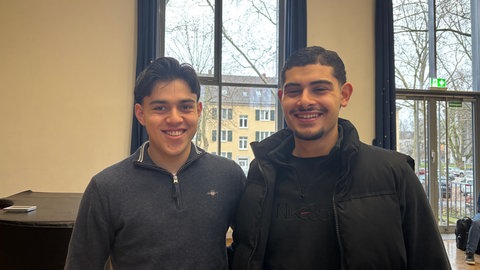 Santiago (links) und Abdurrahman stehen in der Aula des Max-Planck-Gymnasiums. Die 18-Jährigen wollen bei der Landtagswahl wählen gehen.