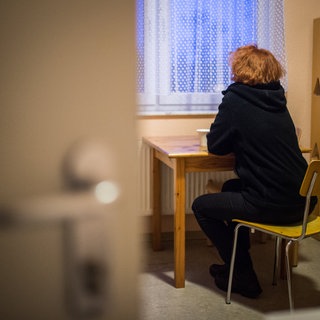 Das Bild zeigt eine Frau, die in einem Frauenhaus aus dem Fenster blickt. Die Frauenhäuser in der Pfalz sind zurzeit ausgelastet - es gibt kaum freie Plätze.