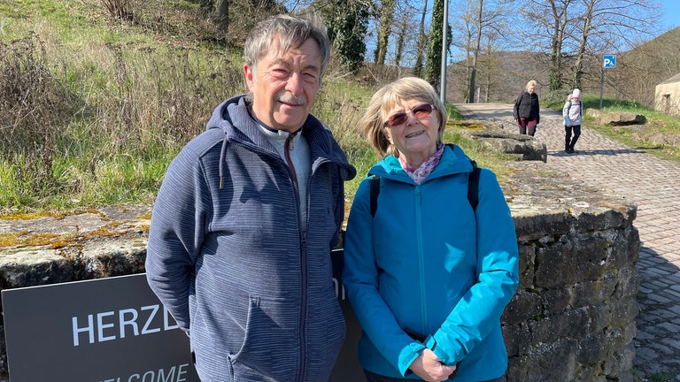 Karin Metz und Dieter Kunz (v.l.n.r.) aus Sachsen stehen am Fuß des Hambacher Schlosses. Sie wollten eine Führung mitmachen und die schöne Aussicht vom Hambacher Schloss aus genießen. Beiden finden den Aktionstag wichtig - vor allem wenn man sich die derzeitige Weltlage mit Krieg und wenig Einigkeit anschaue, ergänzt Kunz.