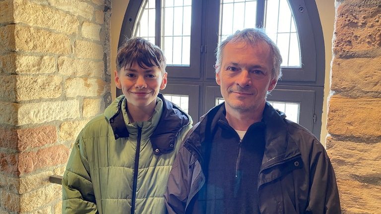Jona und Stefan (v.l.n.r.) aus Rheinzabern stehen vor einem Fenster in der Nähe des Eingangs von einer Ausstellung im Hambacher Schloss. Sie sind extra wegen des Tages der Demokratiegeschichte aufs Hambacher Schloss, um sich die Dauerausstellung "Hinauf, hinauf zum Schloss!" anzusehen und mehr über Demokratie und deren Geschichte zu lernen.