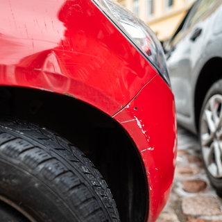 Ein rotes Autos steht mit einem Blechschaden in einer Parklücke.  Die Polizei hat nach einer Unfallflucht nach einem simplen Parkrempler in Mutterstadt viel Aufwand betrieben, um die Verursacherin zu schnappen - mit Erfolg.
